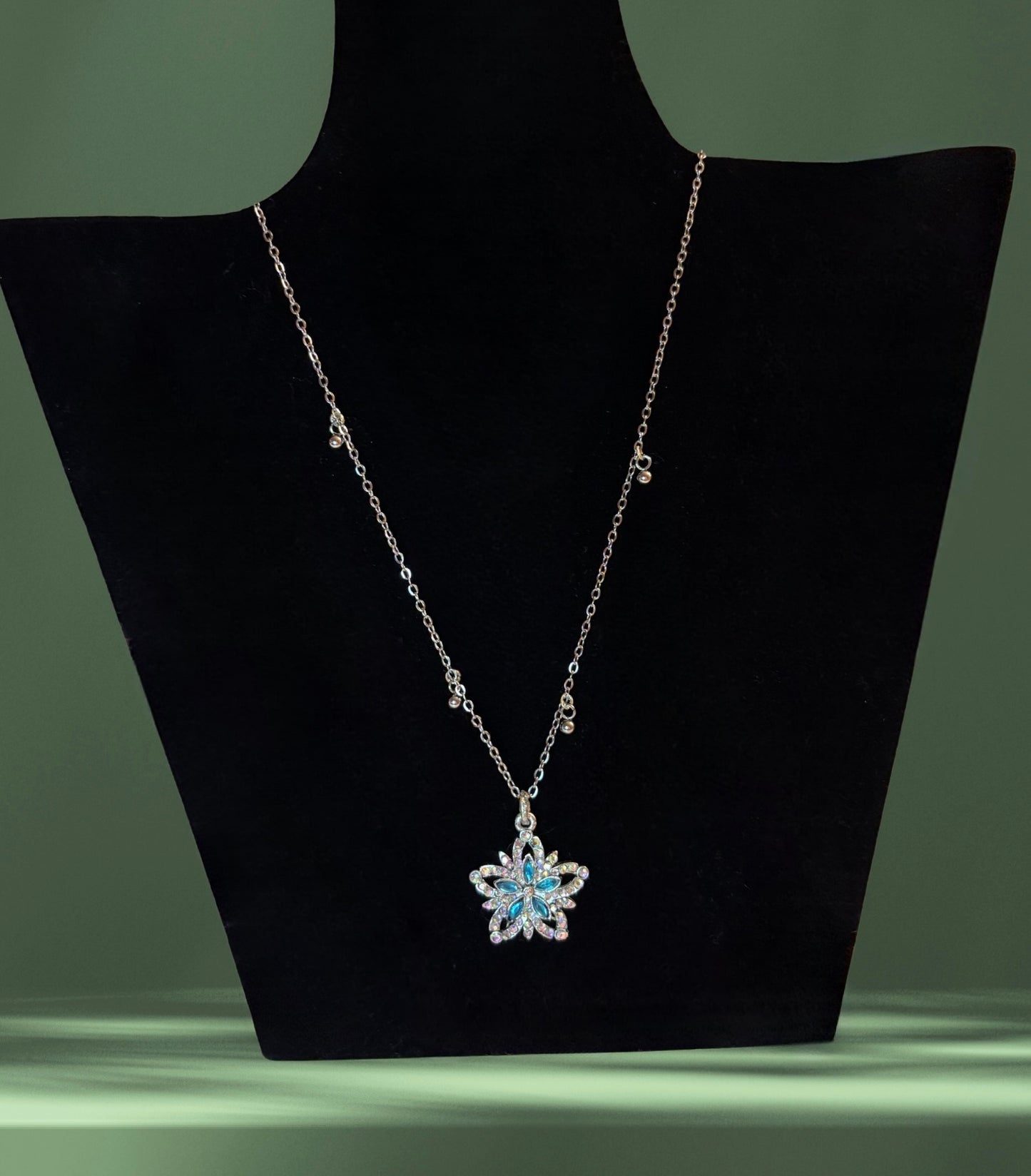 Fairydust halo silver necklace green backround on a stand