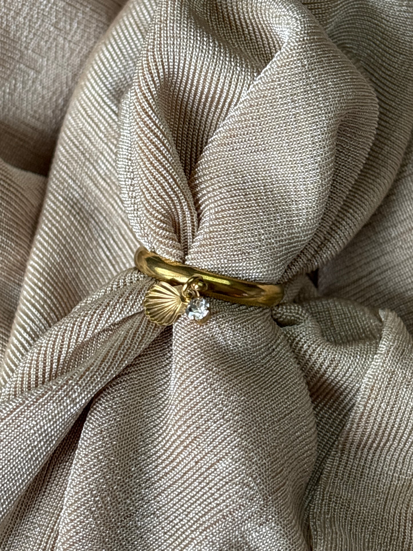 Sea charm gold ring on a beige fabric