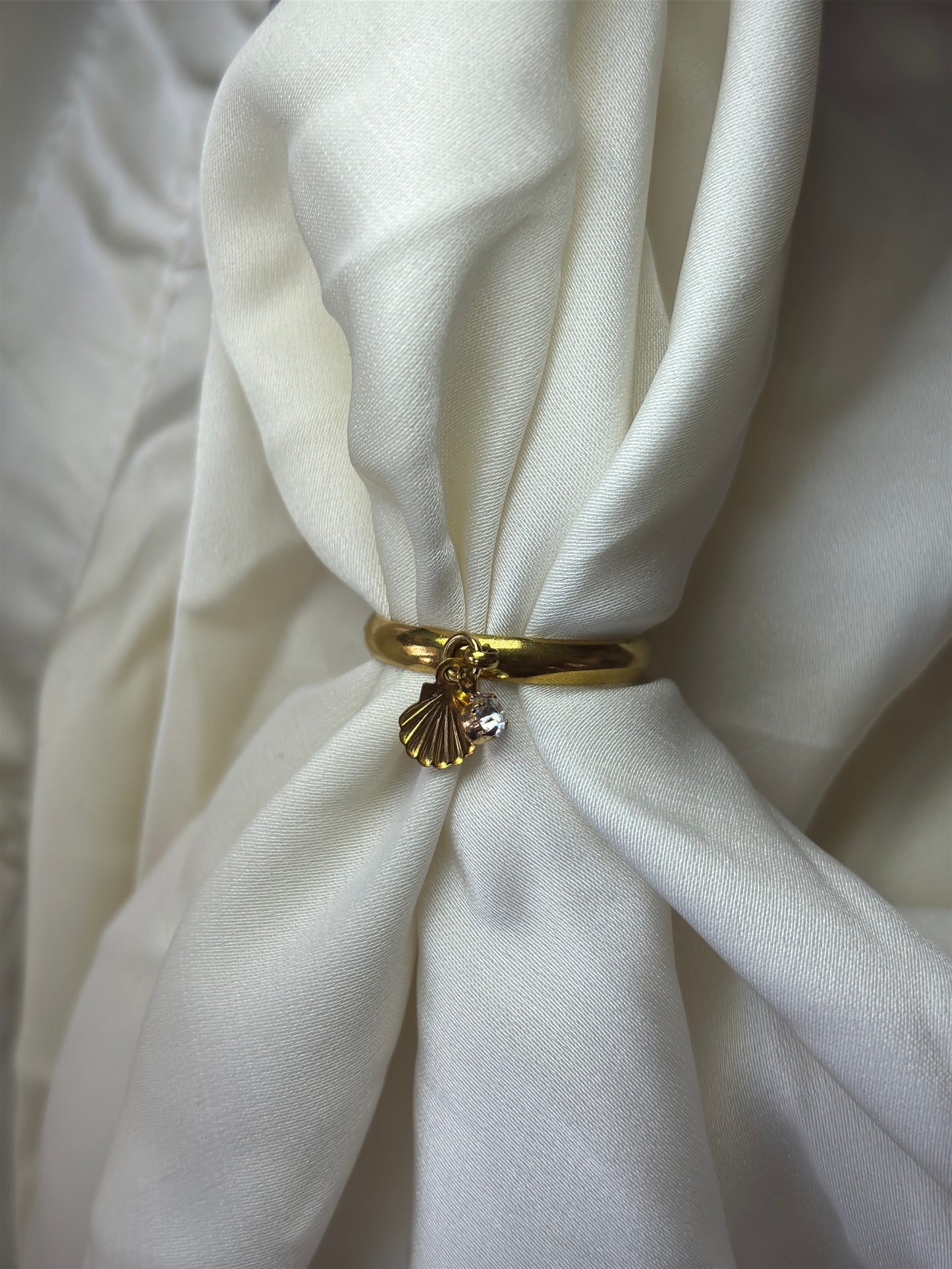 Sea charm gold ring on a white fabric for summer