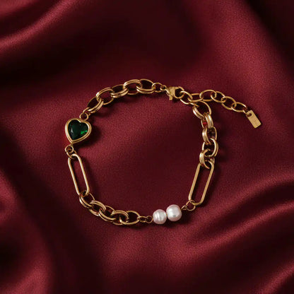 Gold chain bracelet with a heart-shaped green gemstone and pearl on a white background